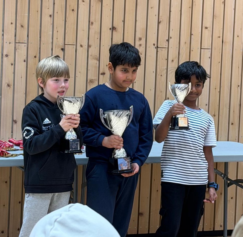 Three students holding trophies at an international event