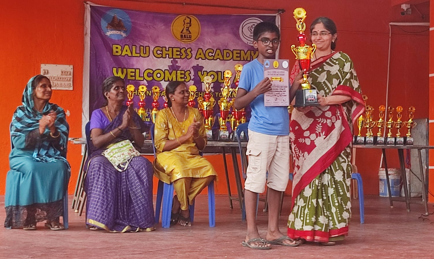 Student receiving trophy and certificate at Balu Chess Academy event